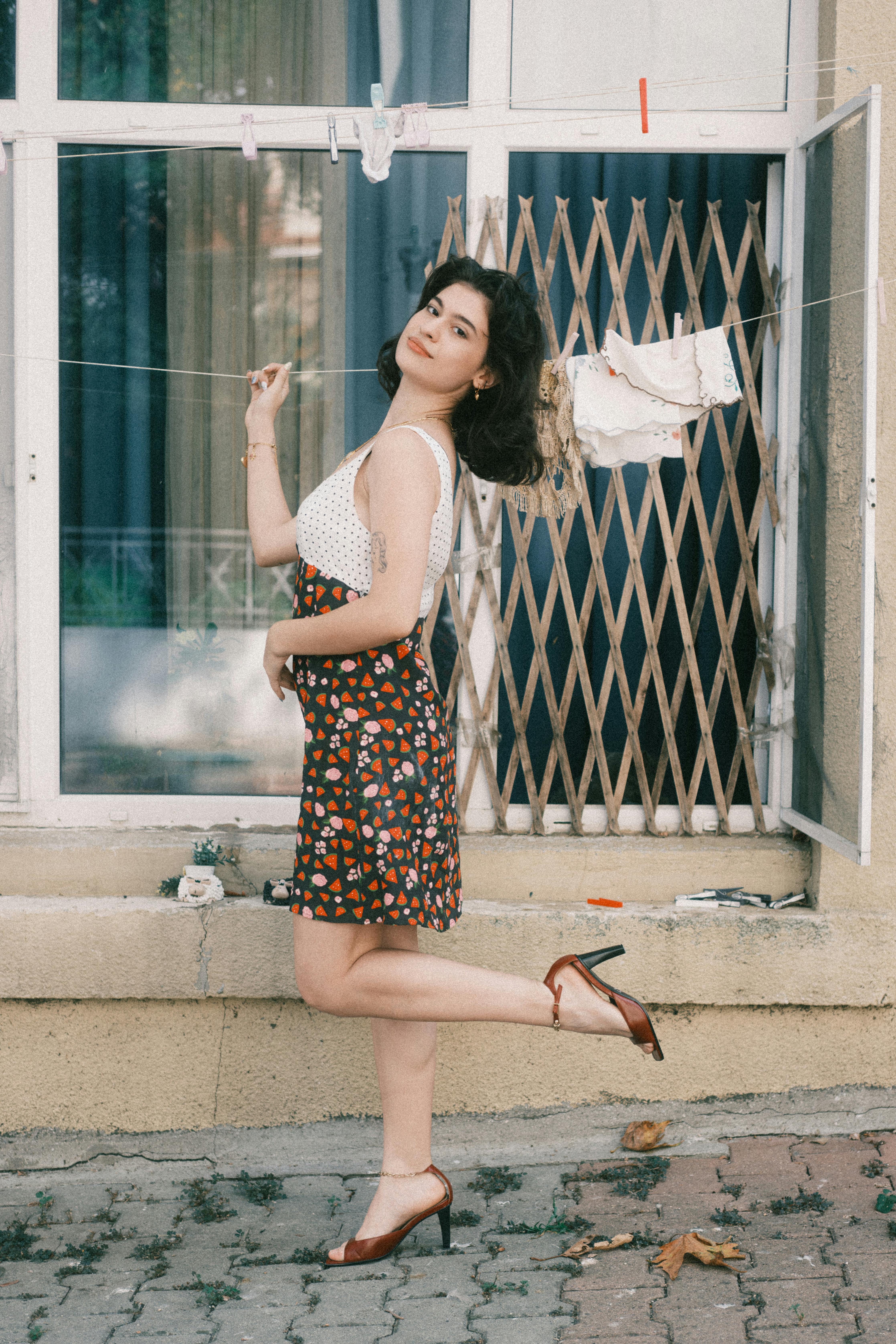 Young woman in stylish dress poses playfully by a window. Urban lifestyle.