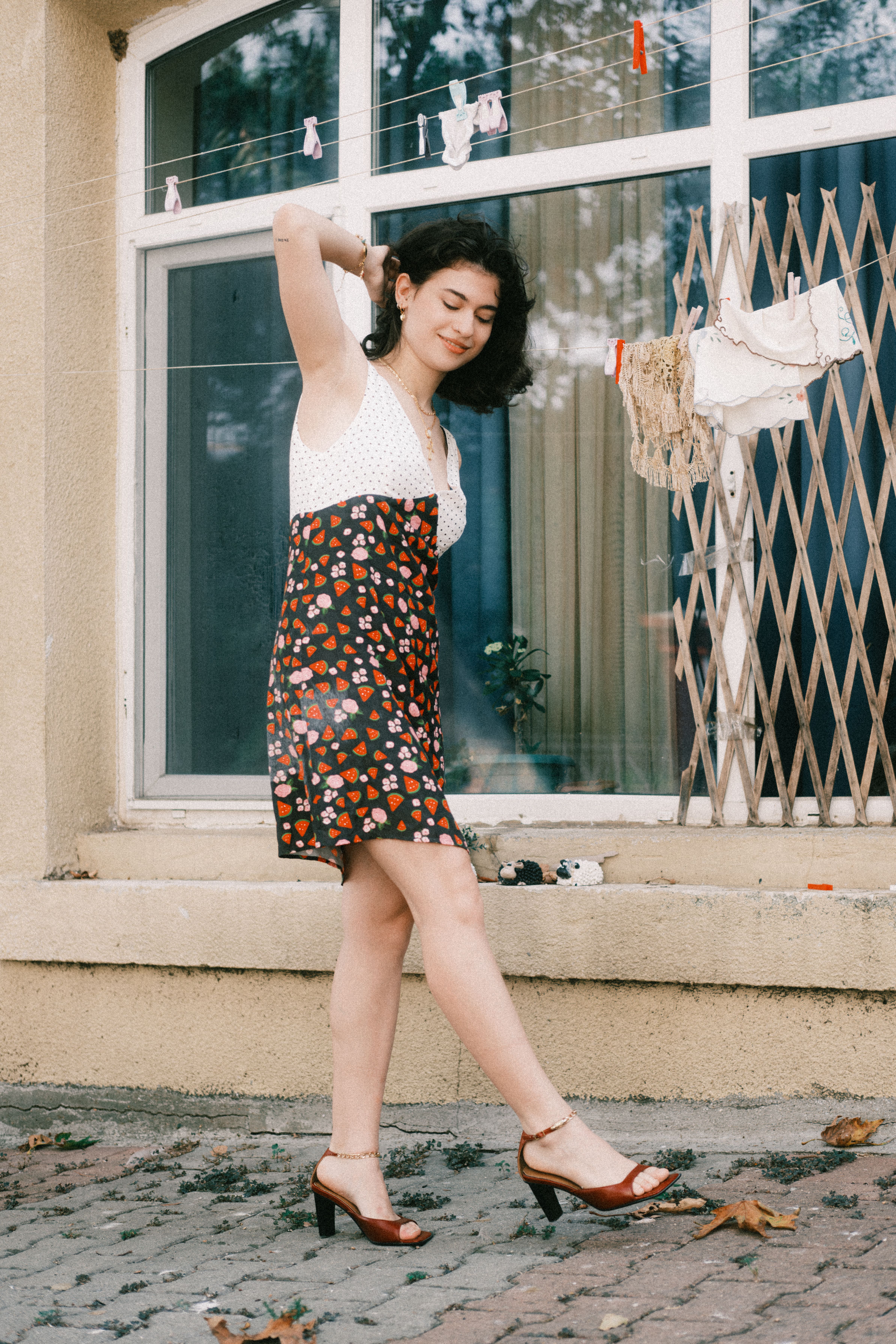 Woman in a floral summer dress poses confidently outdoors.