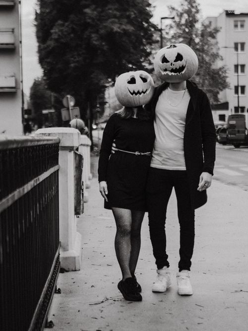 Free A couple wears carved pumpkin heads in a Halloween-themed street scene. Stock Photo