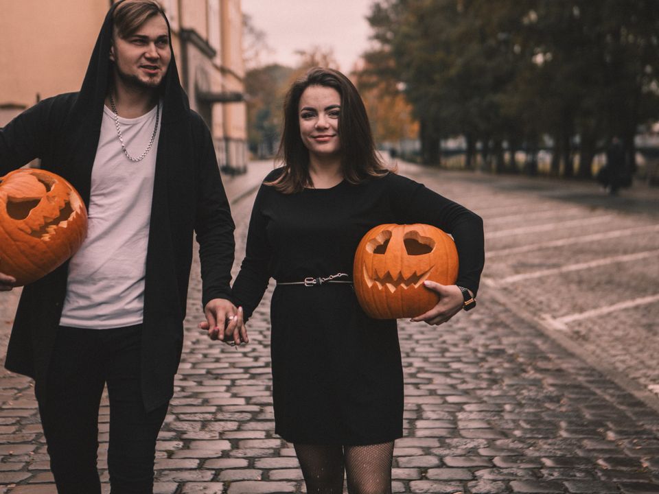 A couple outdoors with carved pumpkins in autumn