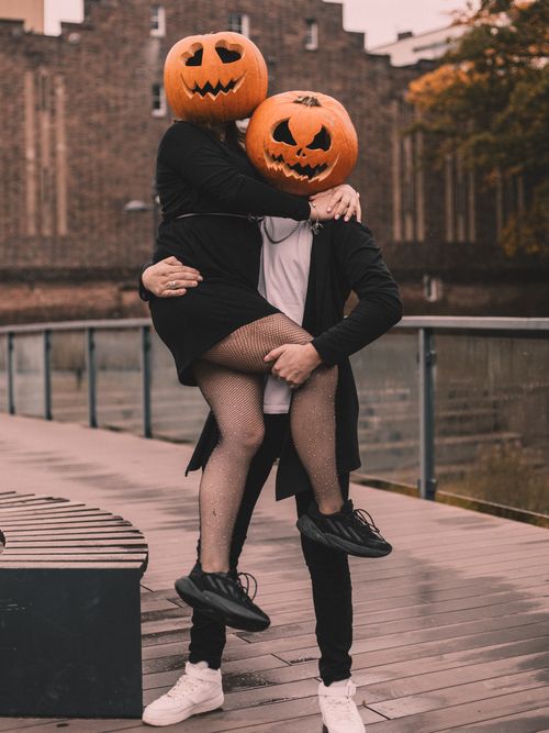 Free Creative Halloween costume photo with a couple wearing pumpkin heads outdoors. Stock Photo