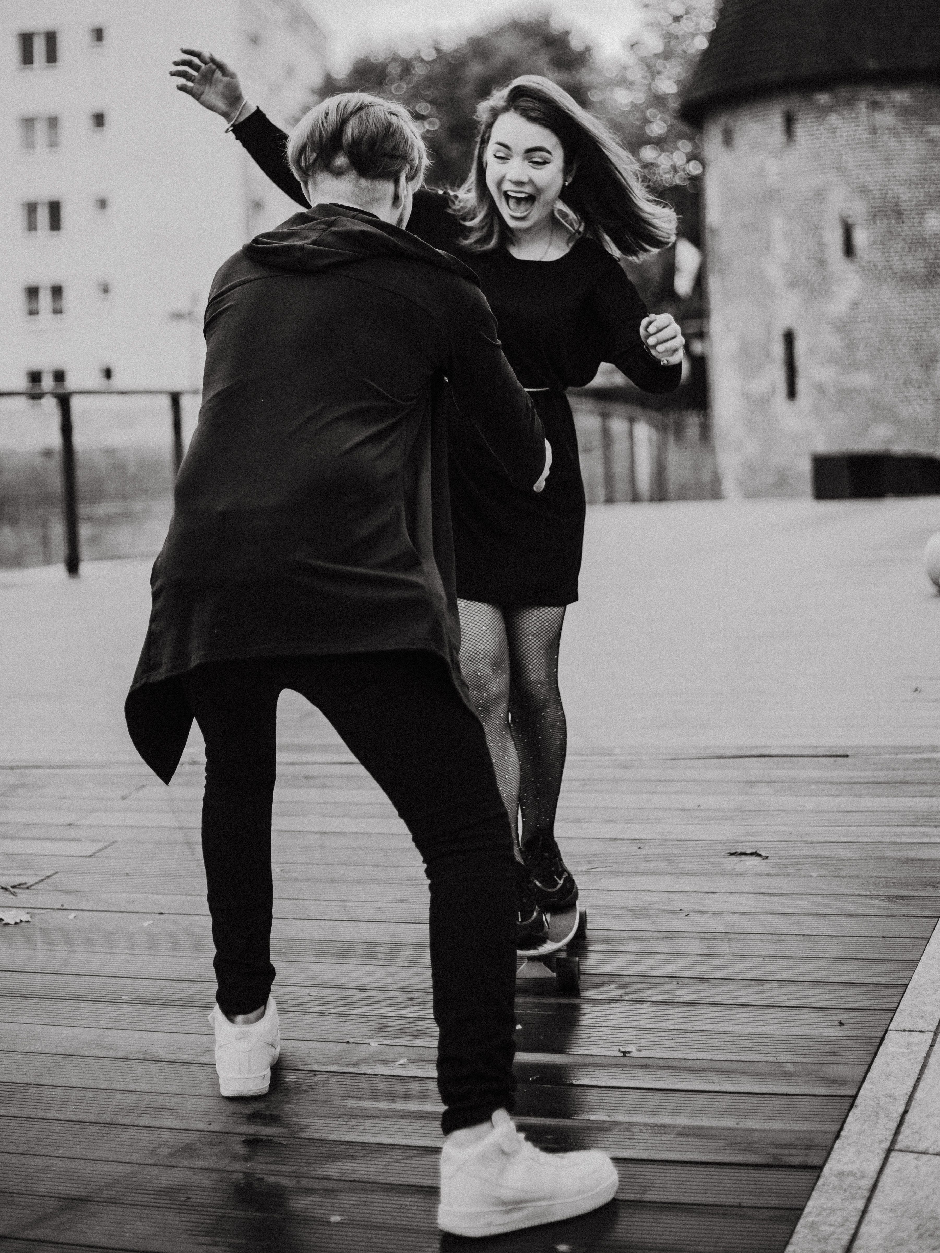 A young couple joyfully dancing outdoors in a city setting captured in black and white.