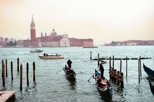 Free Experience the iconic gondolas and timeless architecture of Venice on a calm day by the water. Stock Photo