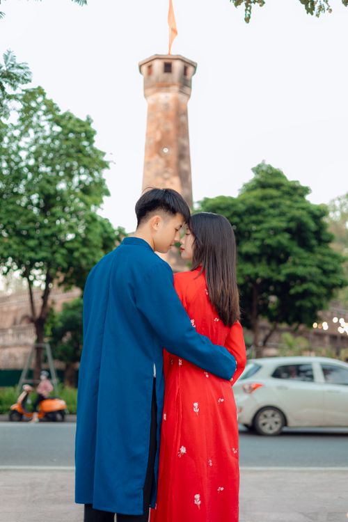 Free Couple in traditional attire embracing near the iconic Hanoi Flag Tower. Stock Photo