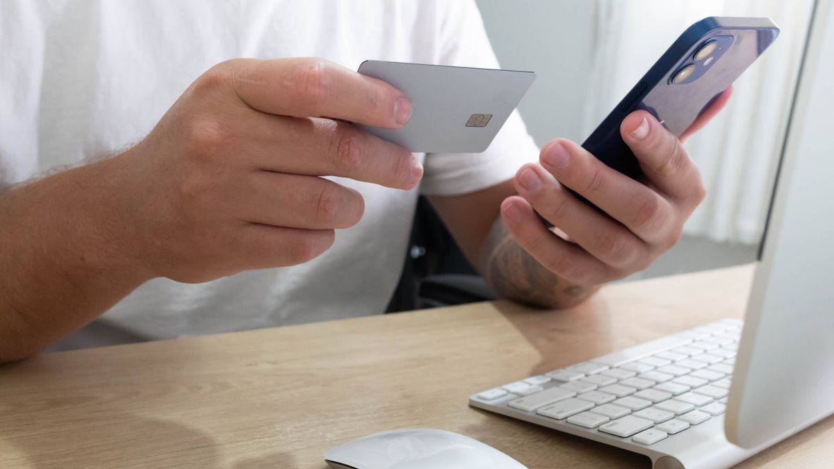 A traveler holding a credit card while booking a hotel on a smartphone in 2026