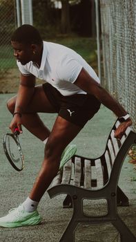 Athlete takes a break on a tennis court bench, holding a racket, showcasing sportsmanship and determination.