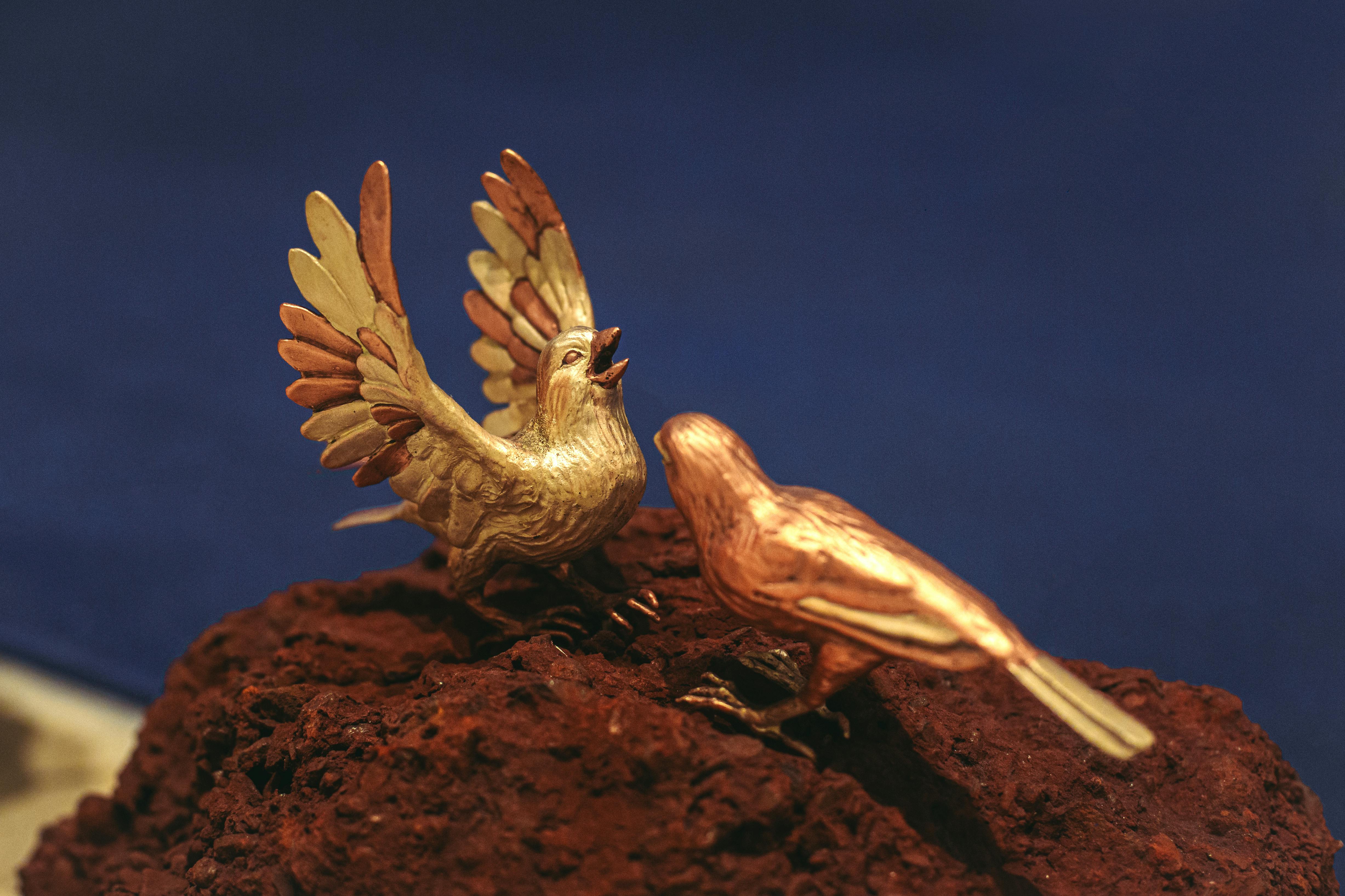 Intricate sculpture of two birds on a rock, showcasing detailed craftsmanship and artistic design.