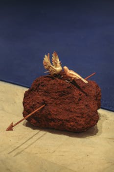 Intricate sculpture depicting birds perched on a rock with arrows, showcased in a museum setting.