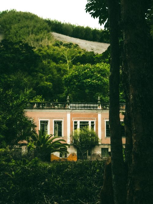 Free Charming pink mansion surrounded by lush greenery and hills, creating a serene and scenic backdrop. Stock Photo