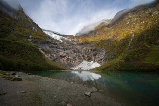 Stunning view of a tranquil lake surrounded by Norwegian mountains and a glacier.