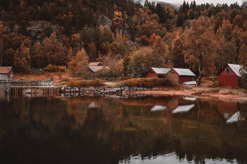 Free Beautiful autumn landscape in Norway with reflection of colorful trees and houses by the waterfront. Stock Photo
