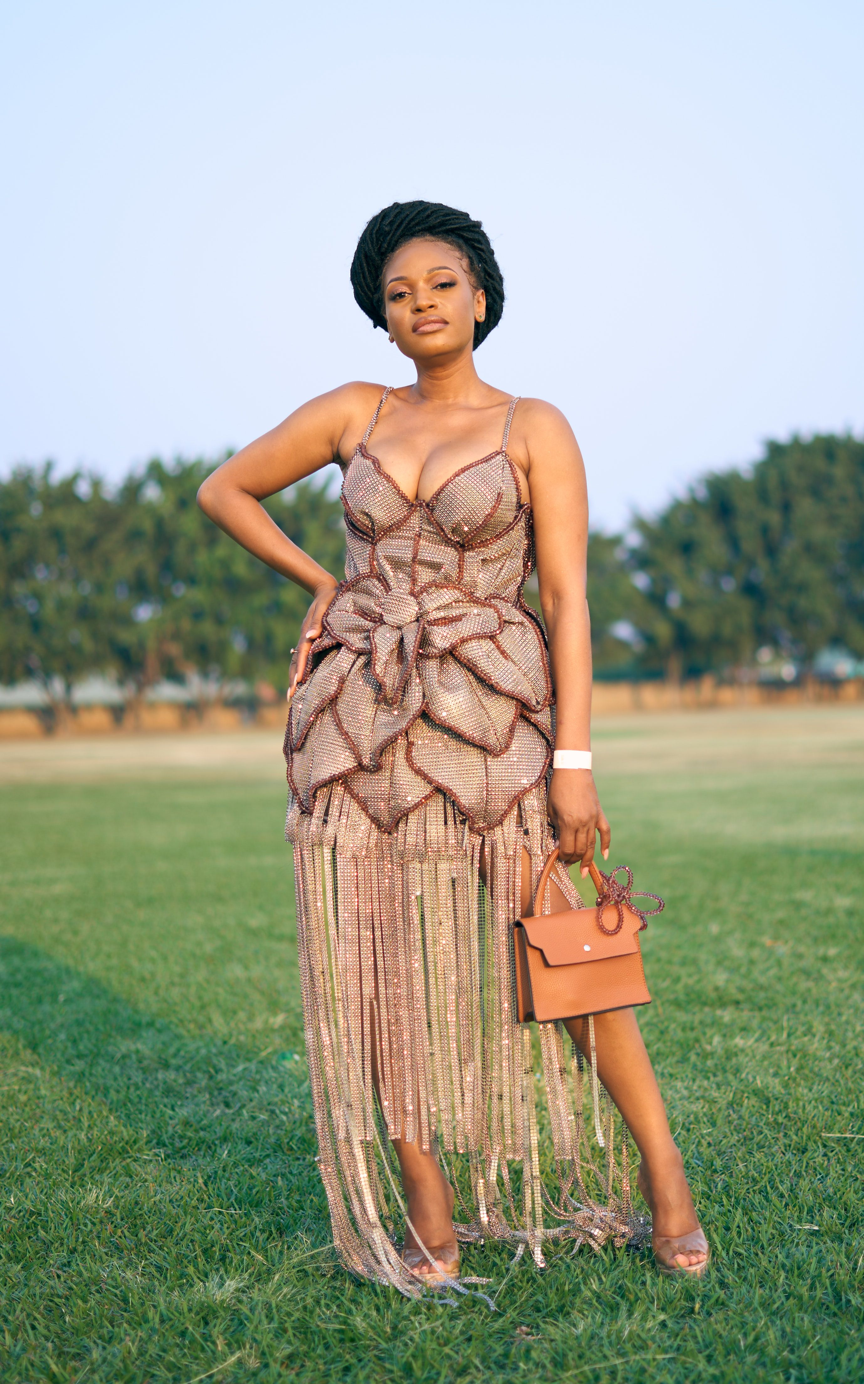 Confident woman posing outdoors in a chic, elegant dress.