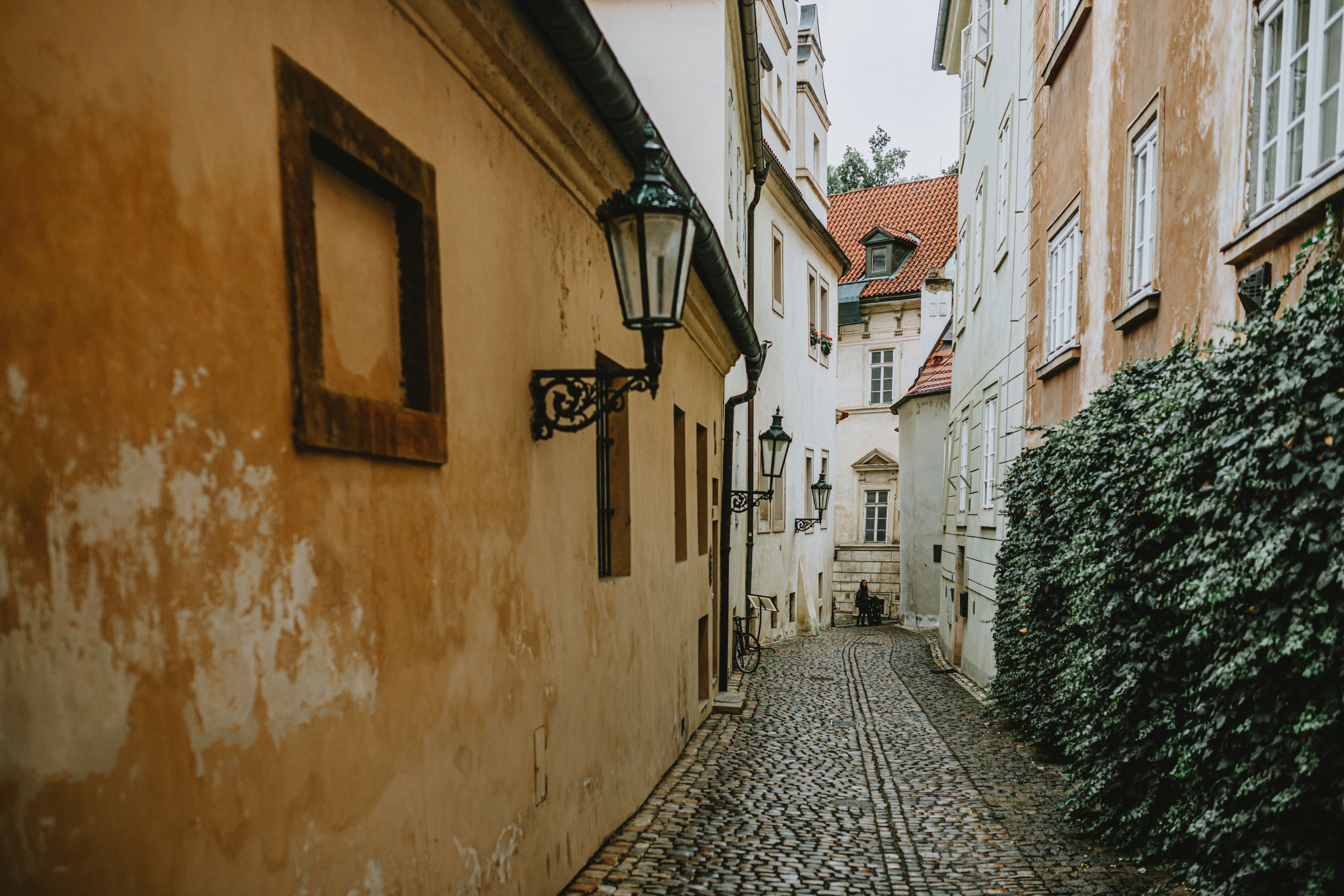 Explore a serene cobblestone alleyway with vintage street lamps in a picturesque European village. — Trójmiasto