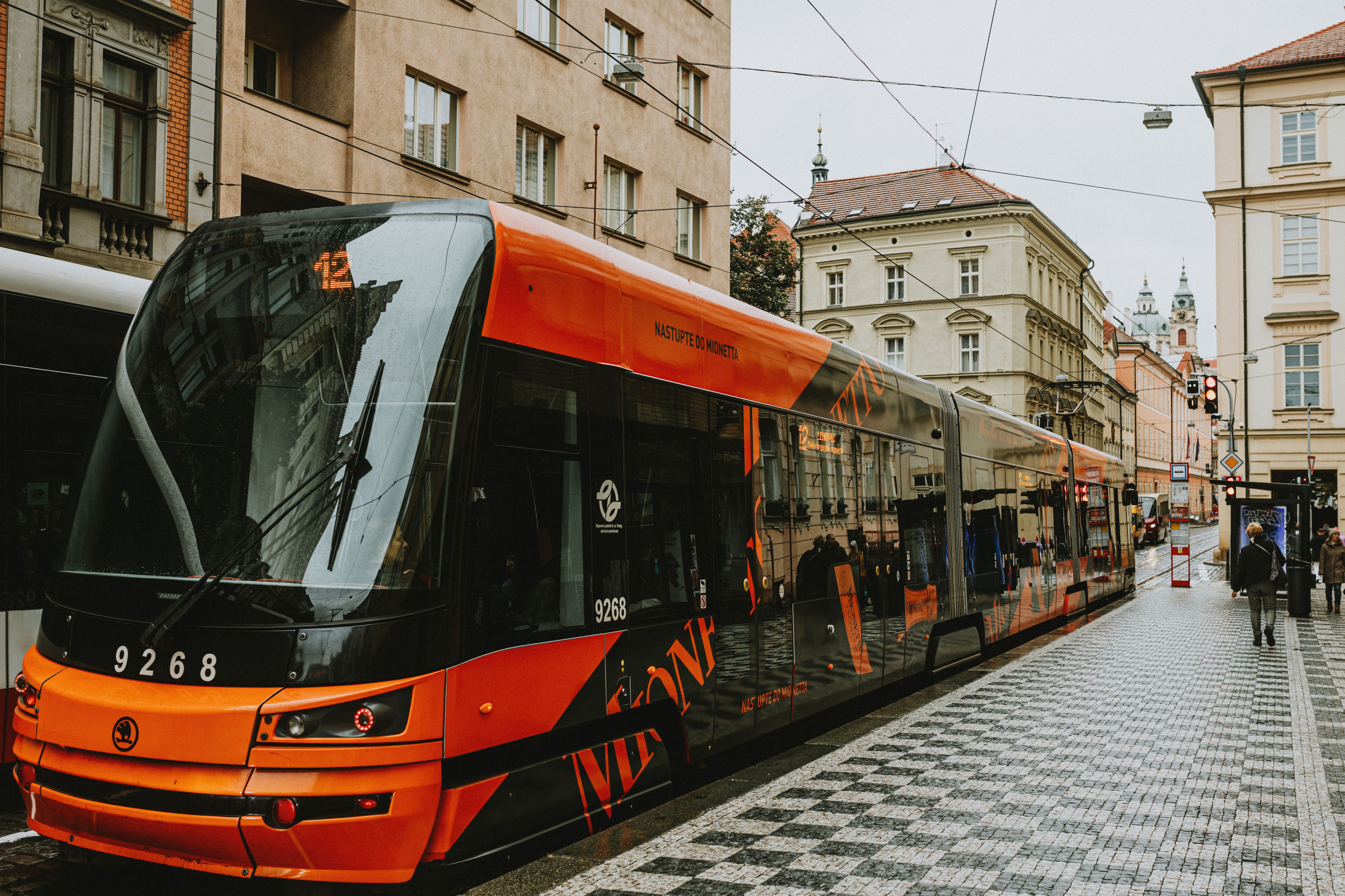 A red tram moving through a street in Prague, representing public transport