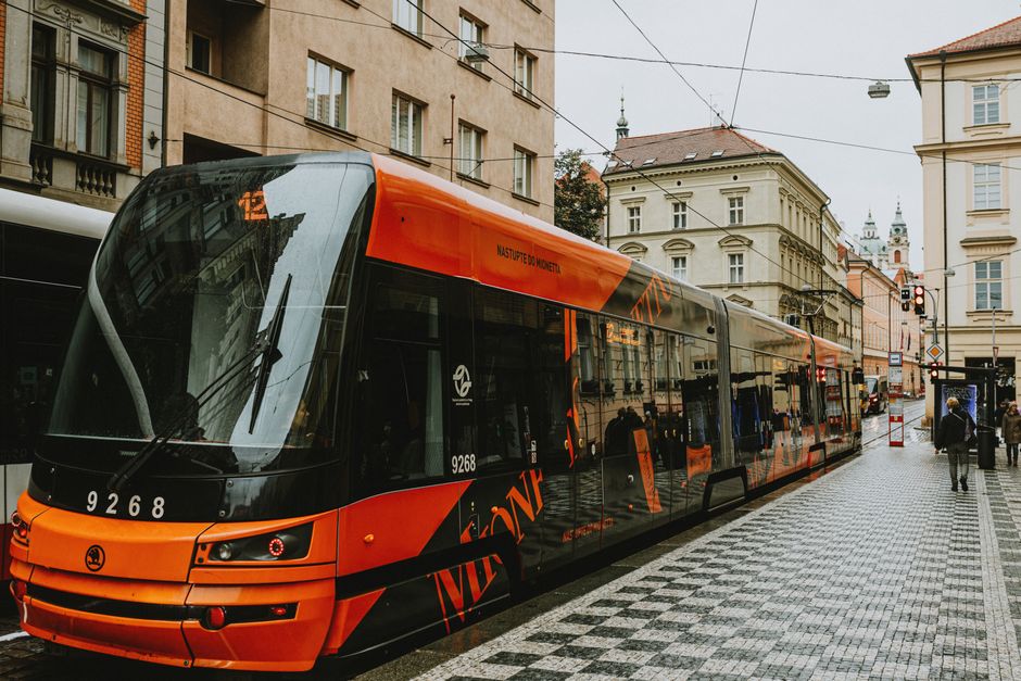 A red tram moving through a street in Prague, representing public transport