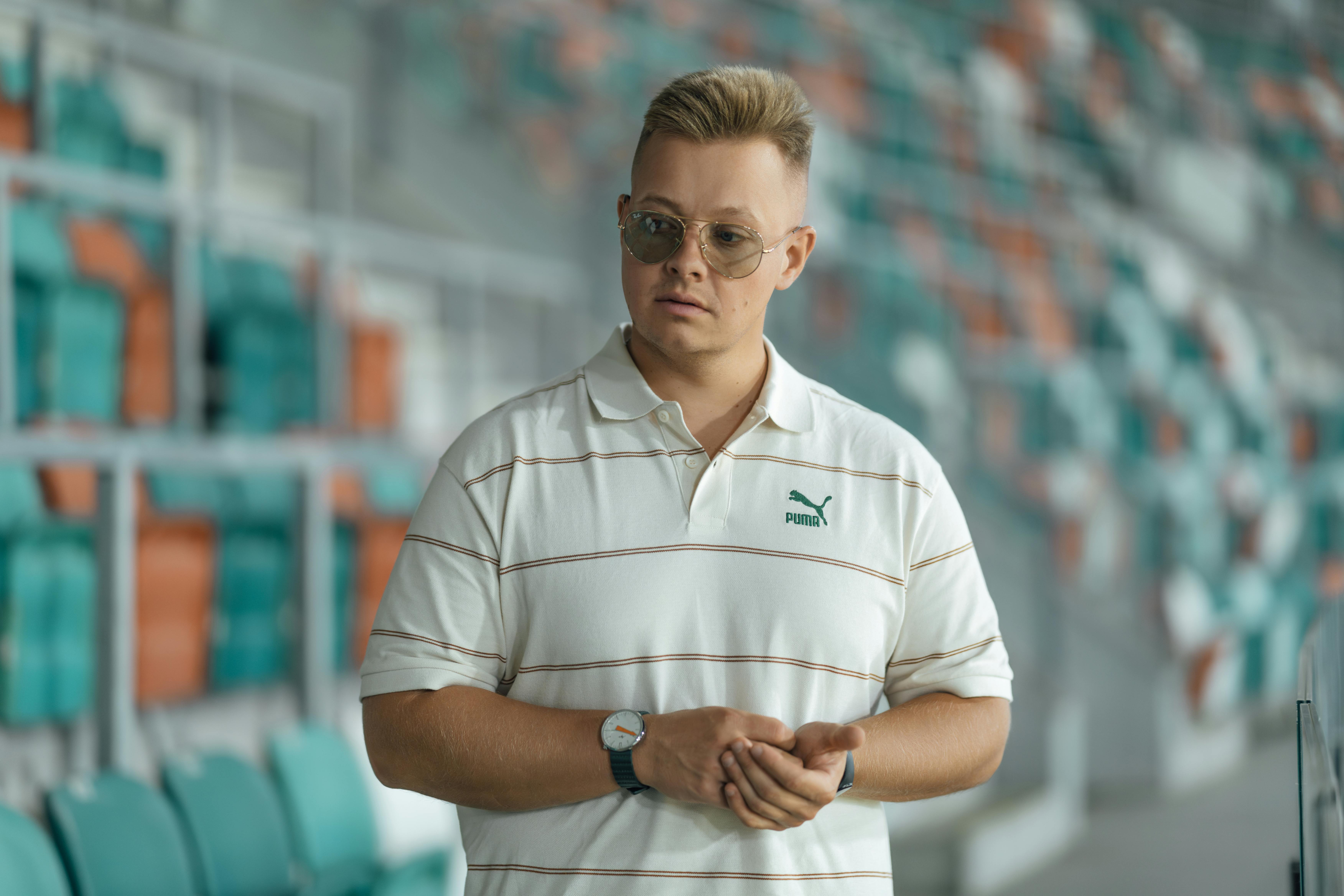 man in a stadium wearing sunglasses and polo shirt