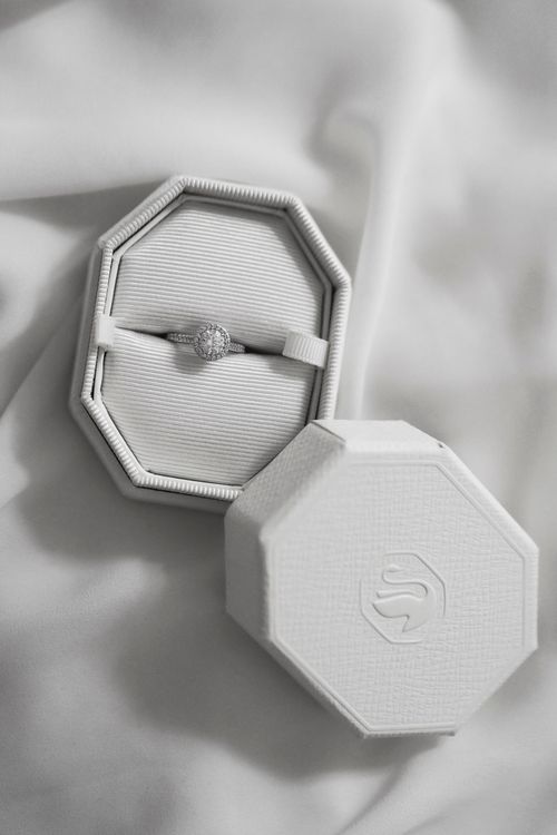 Free Closeup of a diamond engagement ring in an octagonal velvet box on a white fabric. Stock Photo