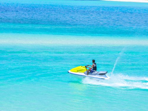 Free Experience thrilling jet ski ride in clear blue Maldives sea with bright skies. Stock Photo