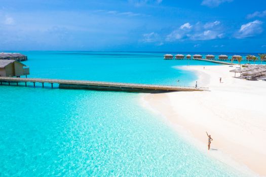 Aerial view of a stunning tropical beach with overwater bungalows in Maldives, ideal for vacation and relaxation.