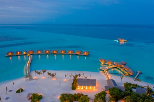 Free Aerial view of overwater villas illuminated at twilight in the Maldives, showcasing a serene tropical paradise. Stock Photo