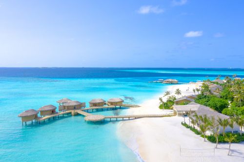 Free A pristine beach resort with overwater bungalows in the Maldives under a clear blue sky. Stock Photo