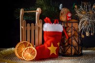 A cozy Christmas still life featuring a stocking, sled, and festive decorations.