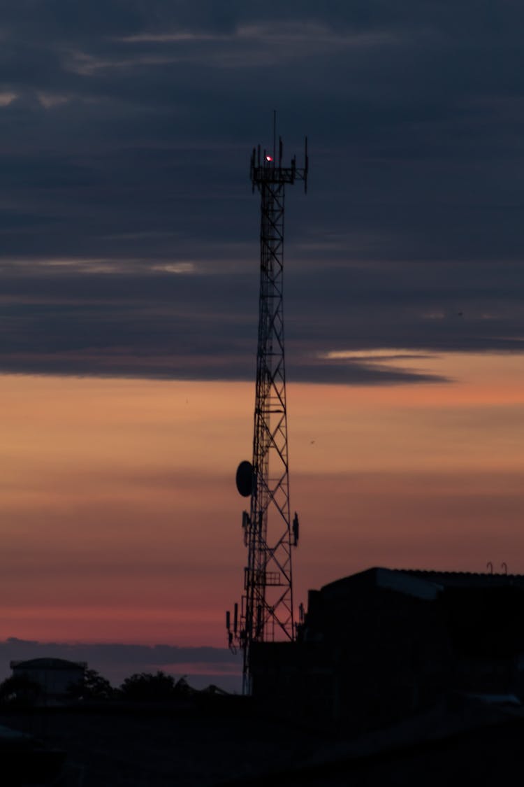 Cellular Tower Against Cloudy Sky In Sunset