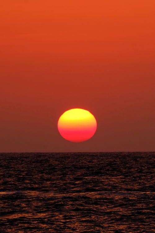 Free Mesmerizing sunset with vibrant orange hues over the ocean horizon. Stock Photo