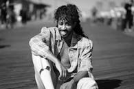 一位卷发的时尚男子面带微笑，在户外摆出单色肖像