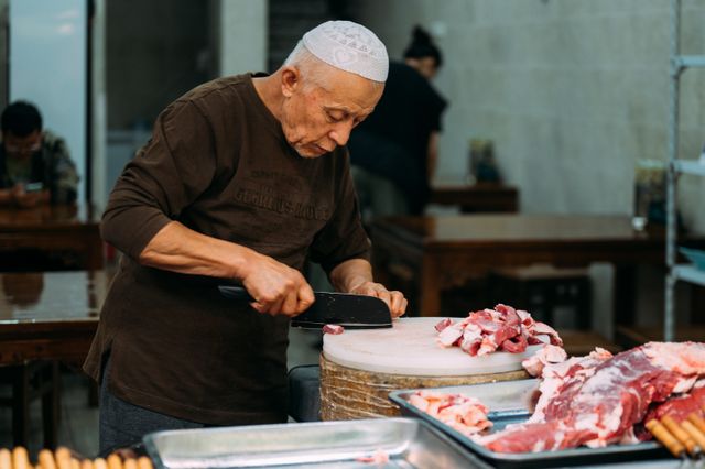 Boucher qui découpe une pièce de viande sur une planche en bois