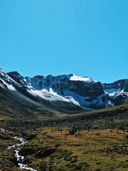Free Majestic snow-covered mountains under a vibrant blue sky and clear day. Stock Photo