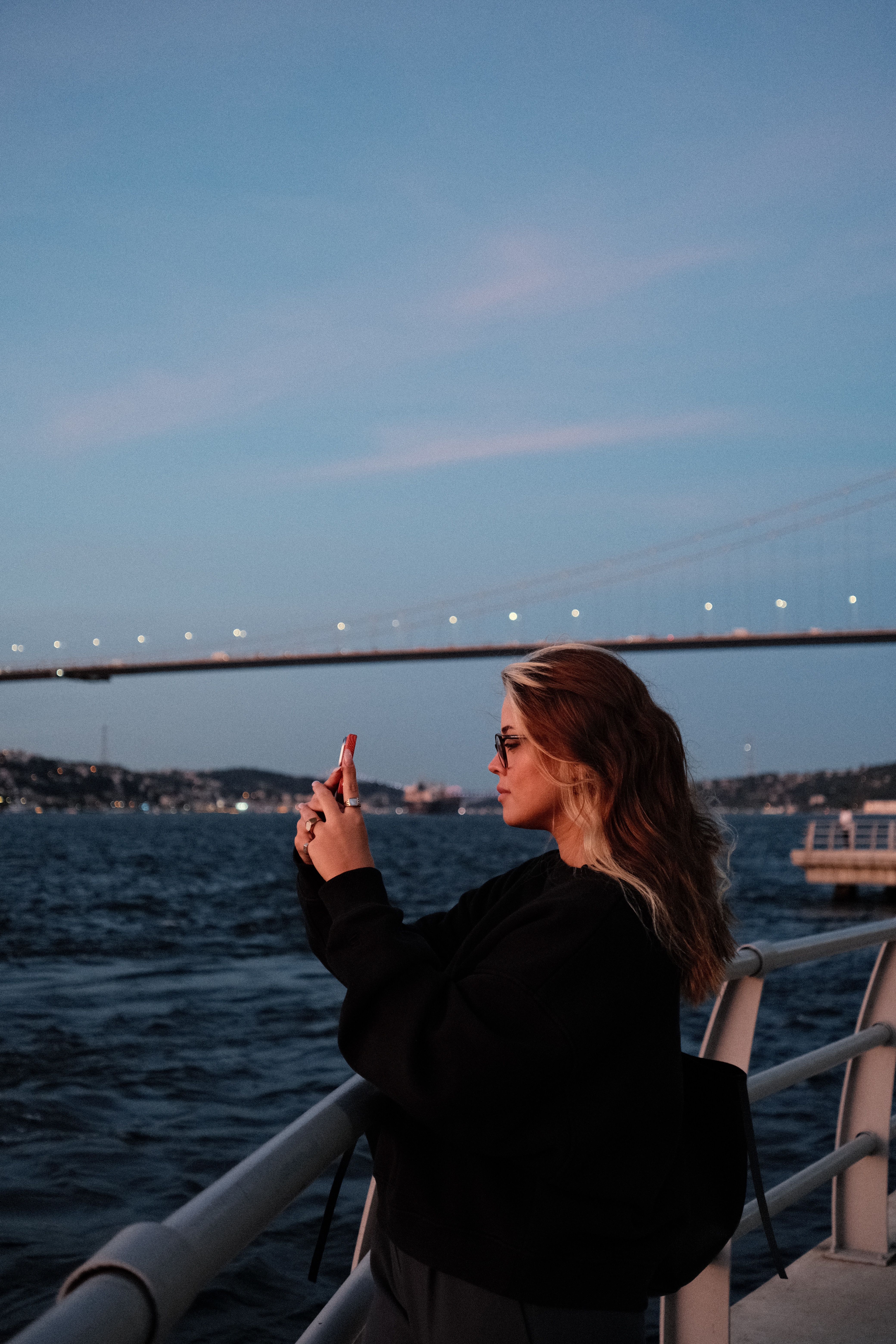 Woman Capturing Bridge at Sunset Reflection · Free Stock Photo