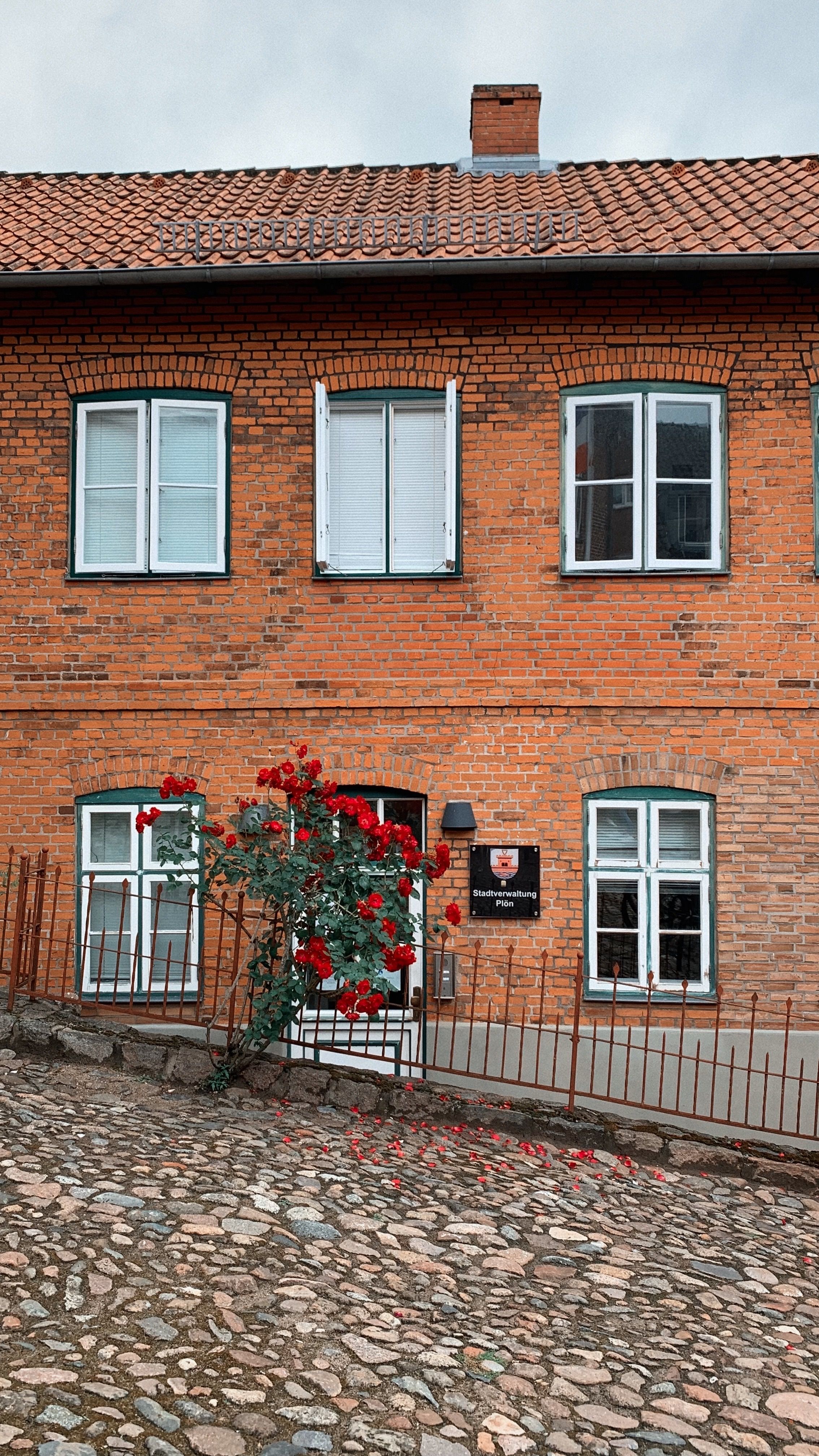 Red brick building in Plön, Germany adorned with beautiful red roses.