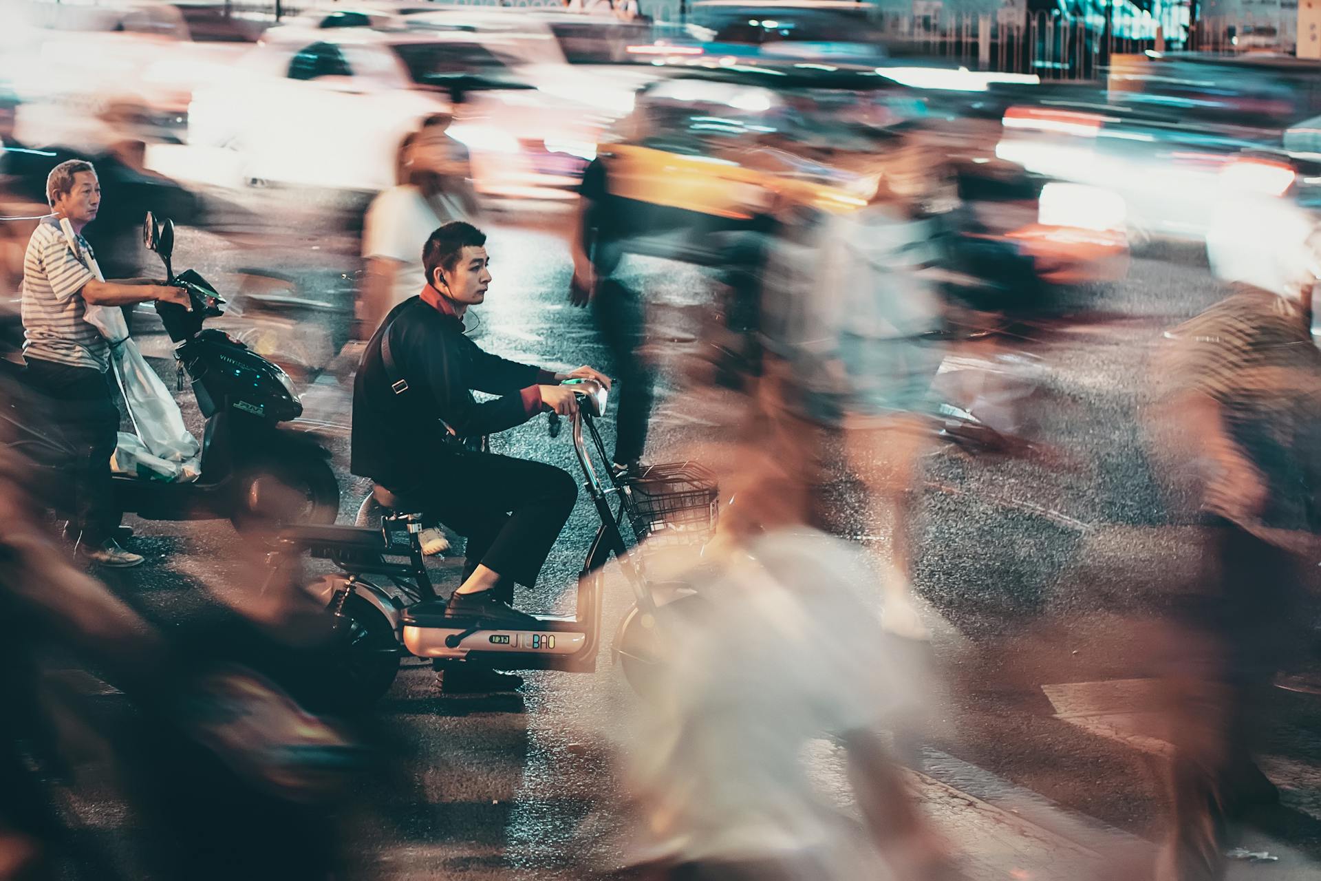 Blurred night traffic and motorcyclists in bustling Beijing street.