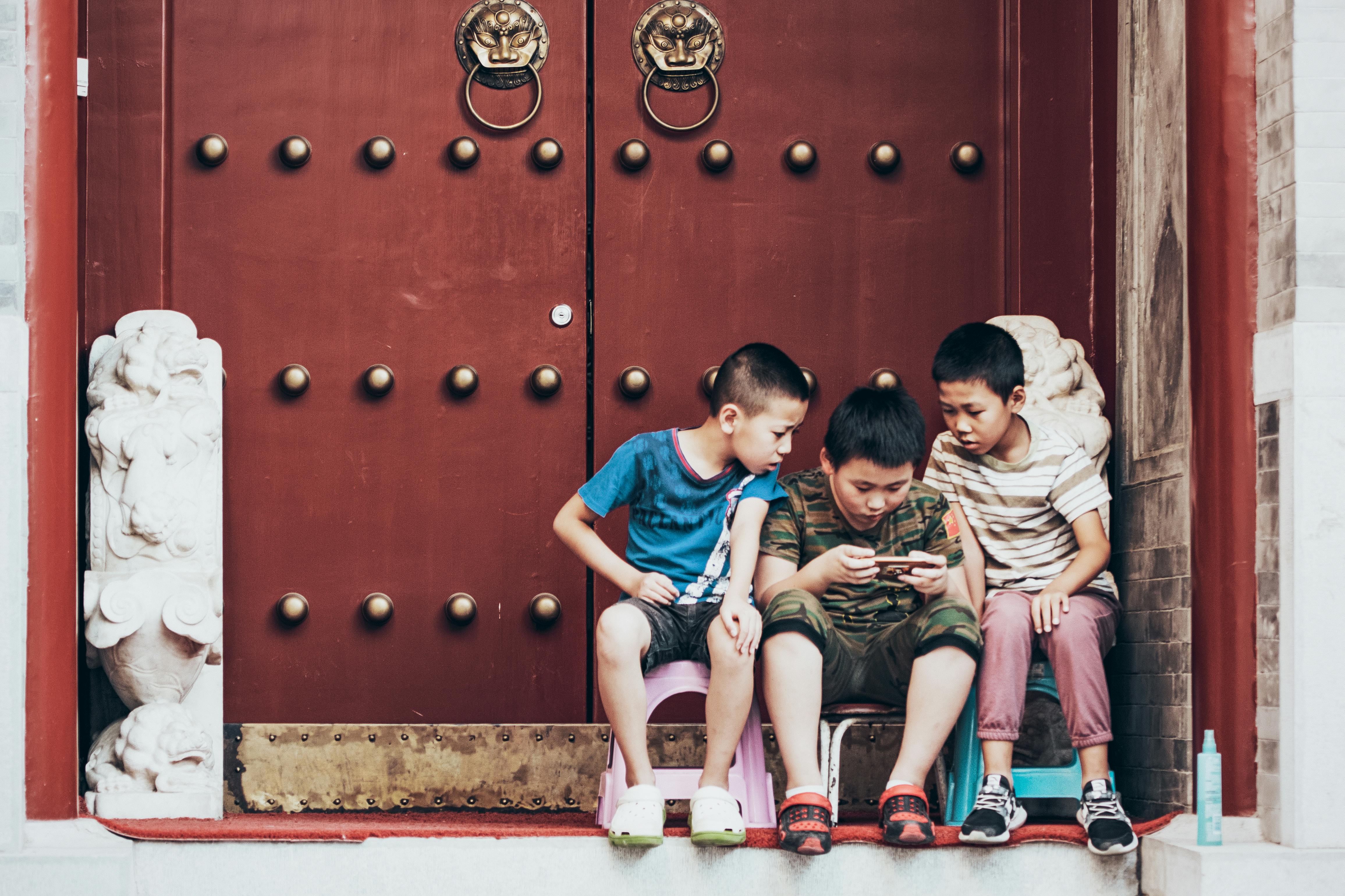 Free Three Boys Sitting Beside Door Stock Photo