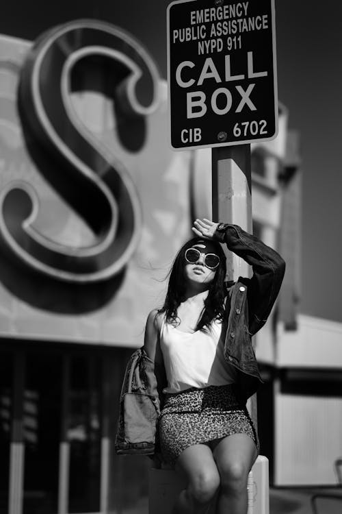 Photo Of Woman Standing Beside Road Sign