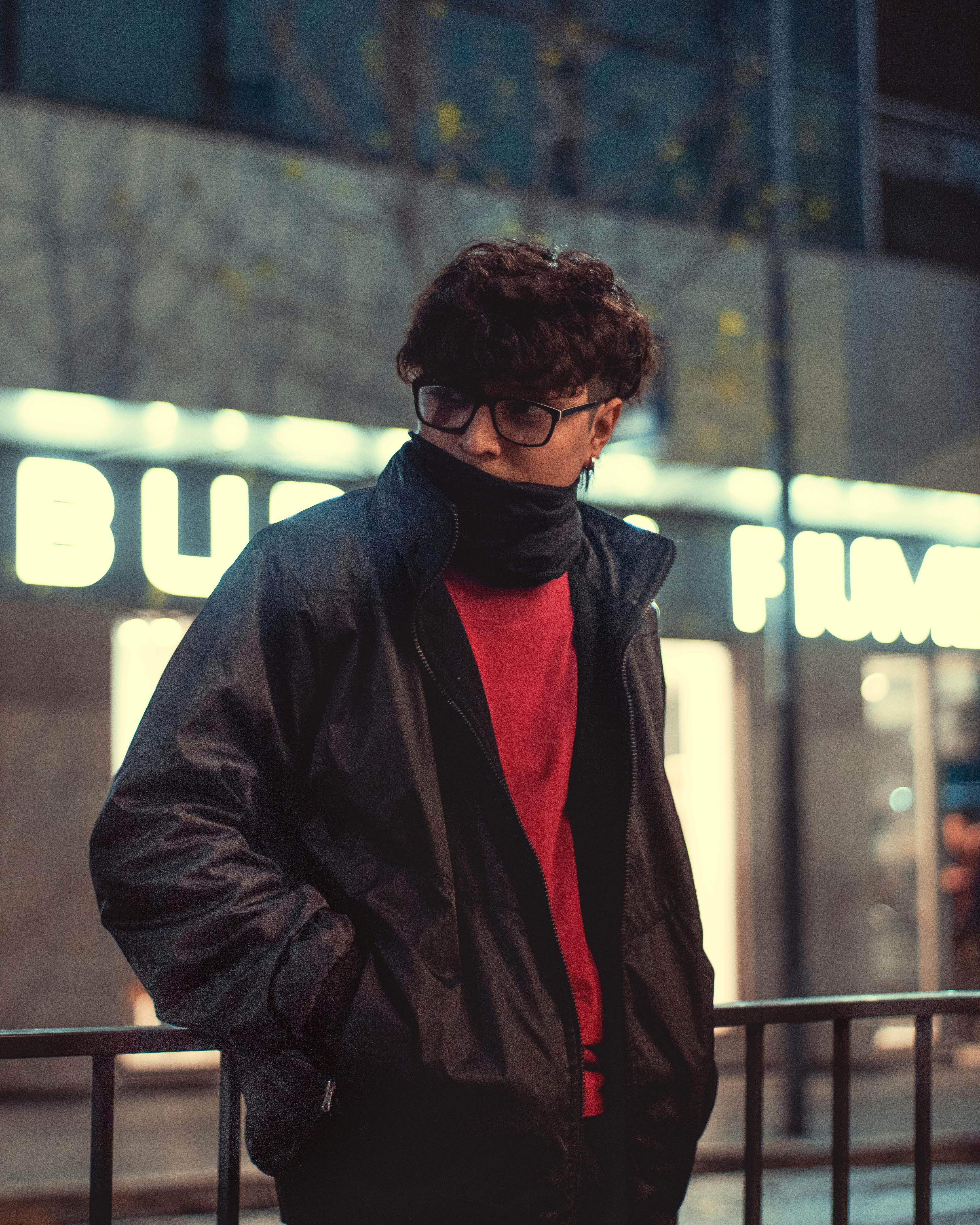 Free Stylish young man in front of illuminated urban backdrop at night. Cool tones and modern fashion. Stock Photo