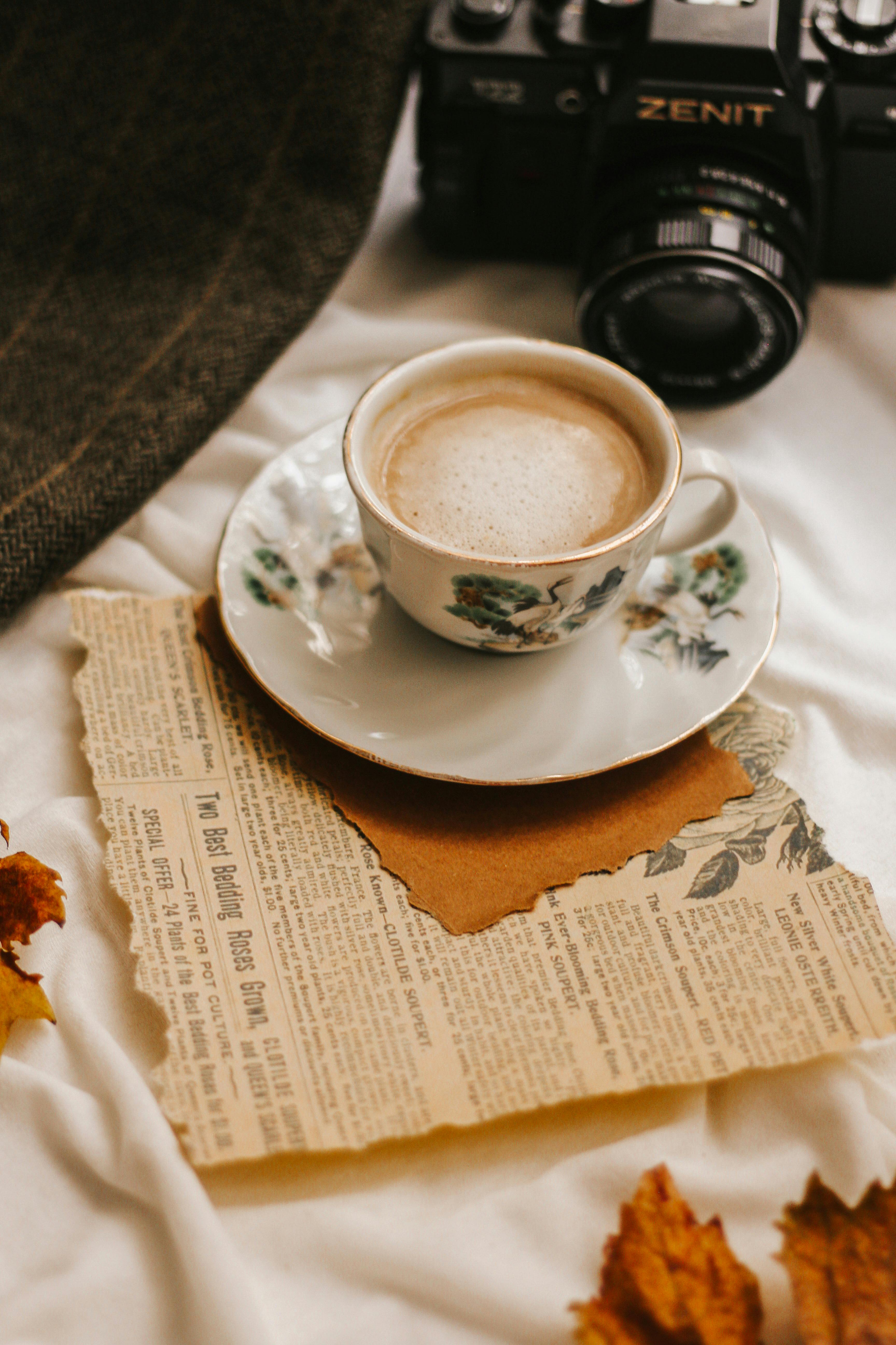 Warm autumn setup featuring a coffee cup, leaves, and a vintage camera.