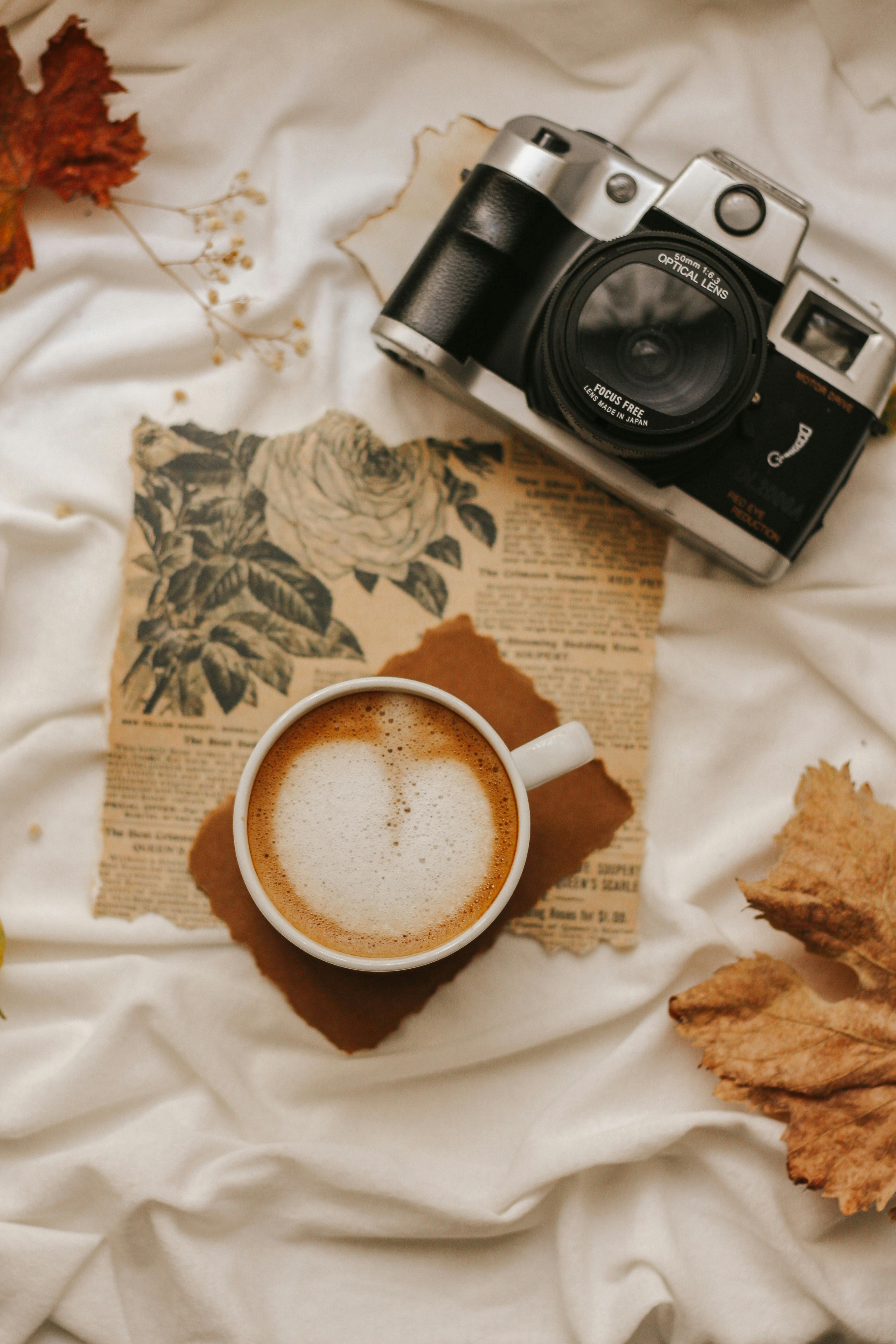 Vintage camera and cappuccino on a cozy autumn-themed setup.
