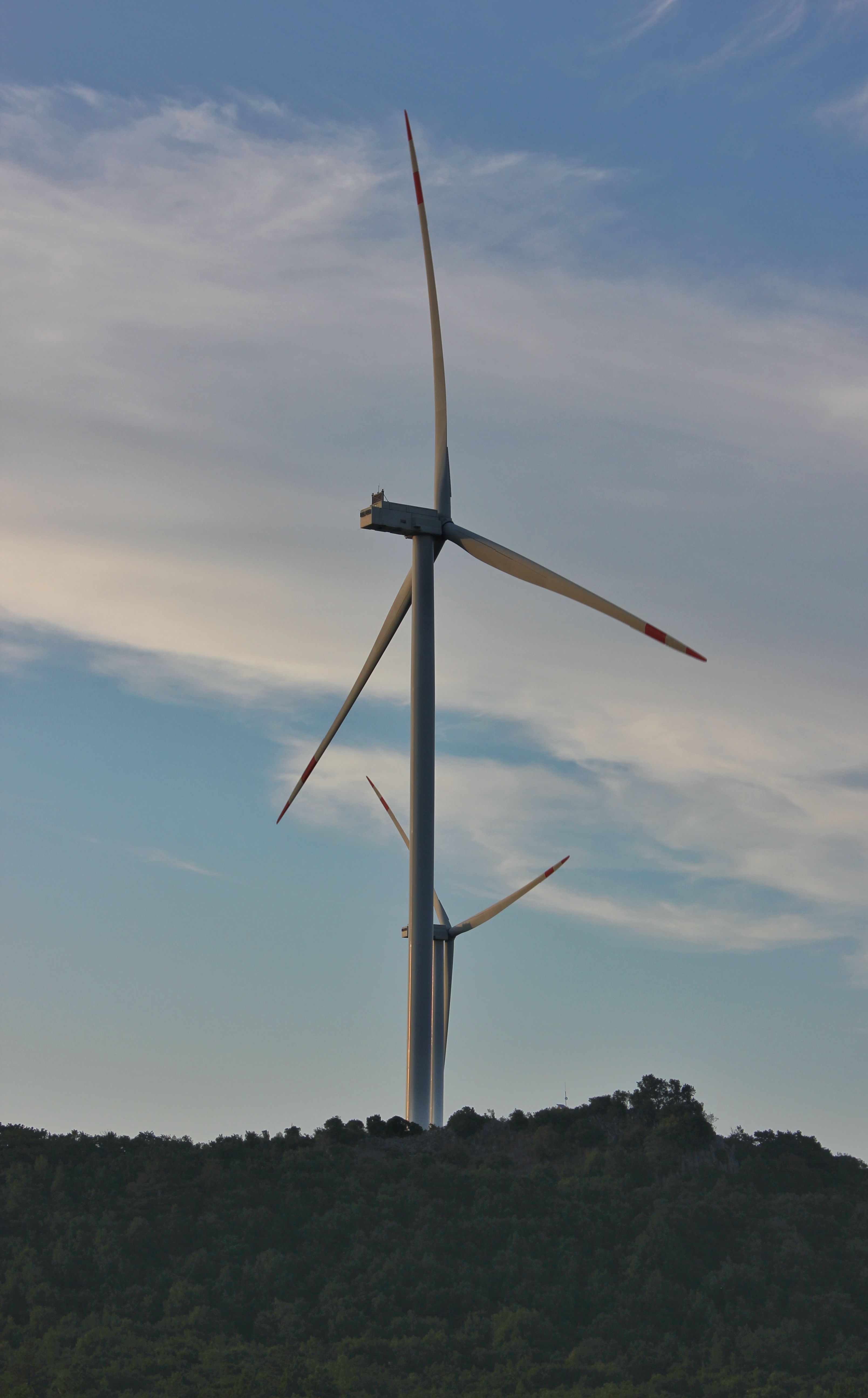 Wind turbines on green hillside under clear sky