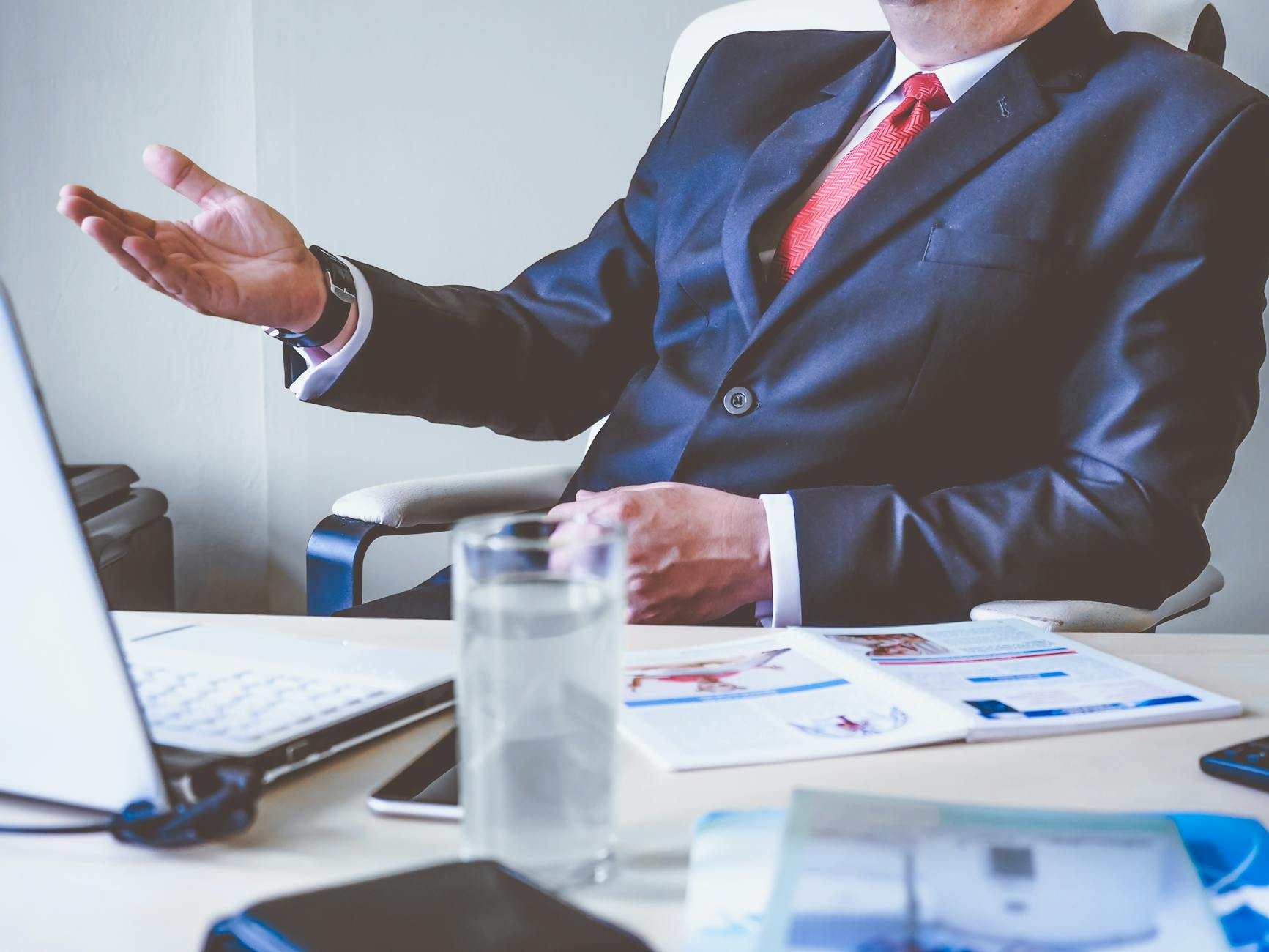 A photo of a business boss in a suit, one hand raised