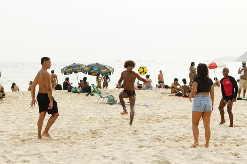 Free A lively beach scene captures people playing volleyball in Rio de Janeiro's sunny beach setting. Stock Photo