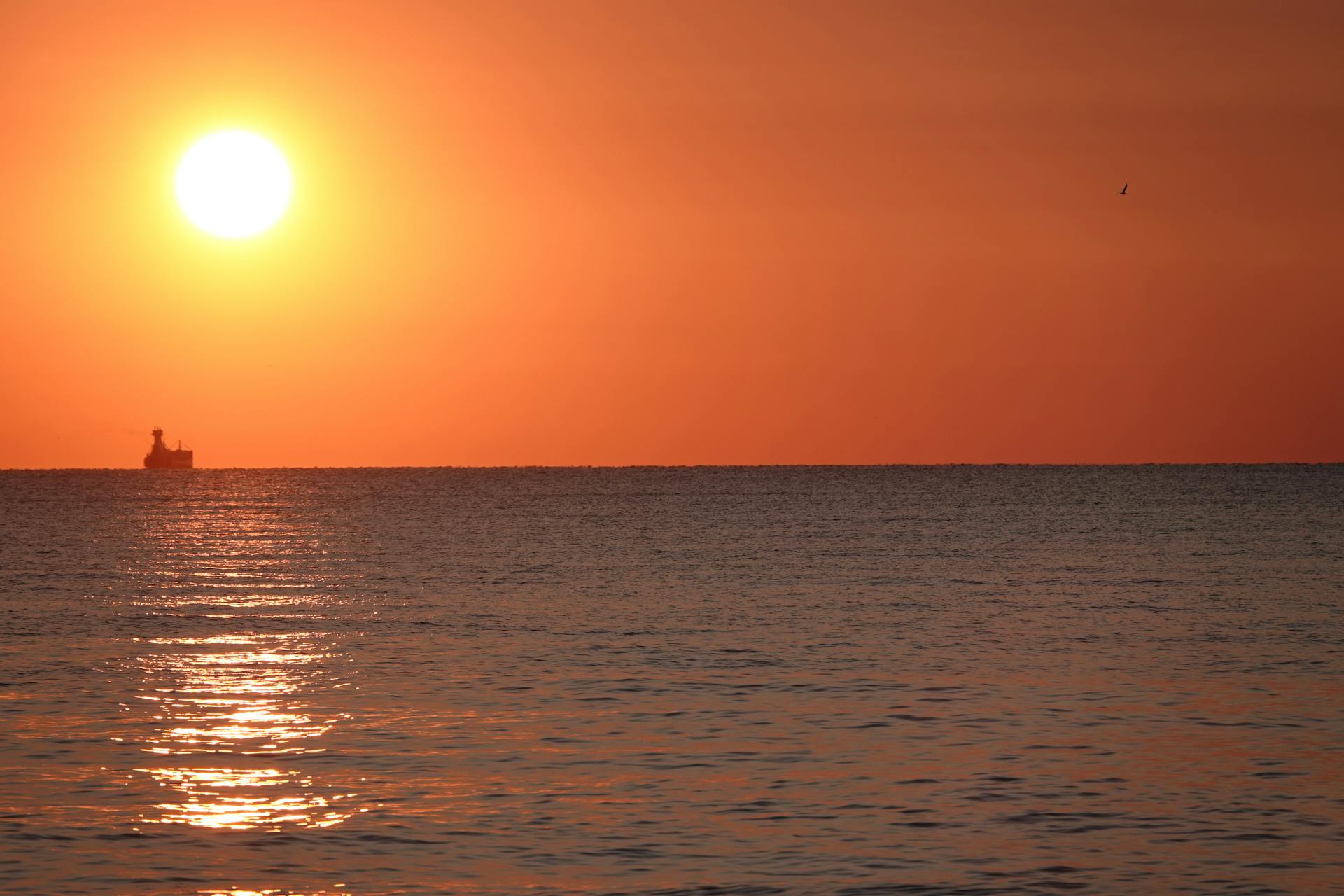 Tranquil sunset over Lake Erie with silhouetted boat and vivid sky reflection.