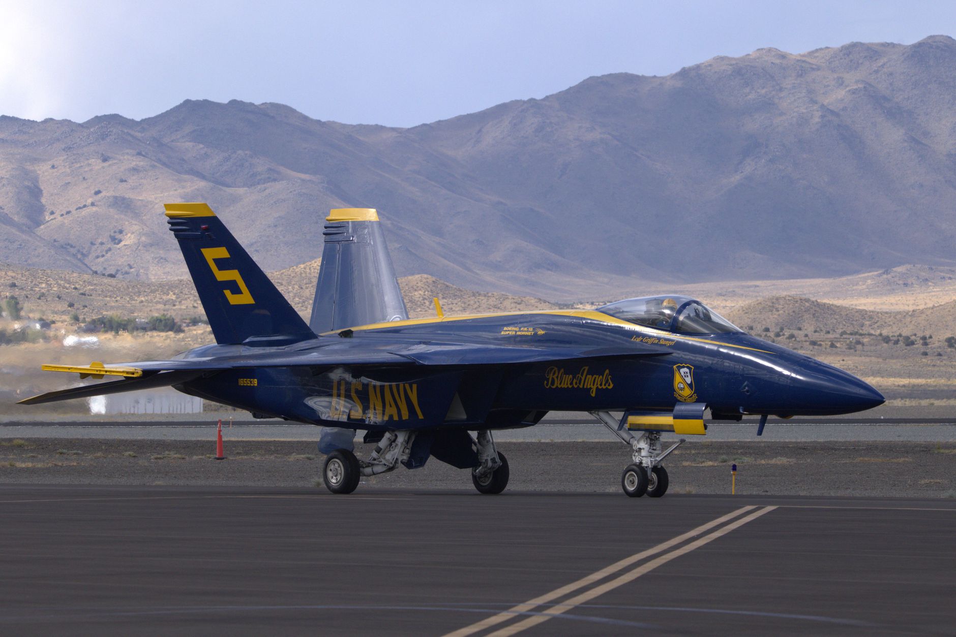 Blue Angels F/A-18 Hornet jet from US Navy on runway in desert landscape.
