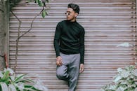 一位戴着墨镜的时尚年轻人在户外对着金属百叶窗自信地摆姿势