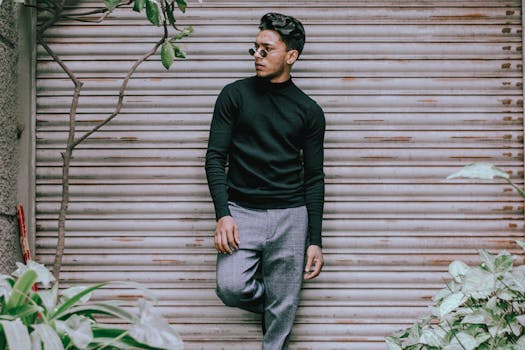 一位戴着墨镜的时尚年轻人在户外对着金属百叶窗自信地摆姿势