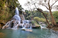 郁郁葱葱的绿色植物环绕着美丽的瀑布，一位孤独的徒步旅行者映入眼帘，展现出宁静的自然景象