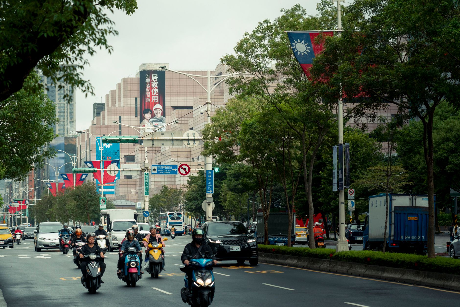 A vibrant street scene in Taipei with scooters and Taiwan flags displayed prominently.