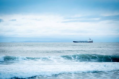 Free Serene seascape capturing a ship in the distance with gentle waves and a cloudy sky. Stock Photo