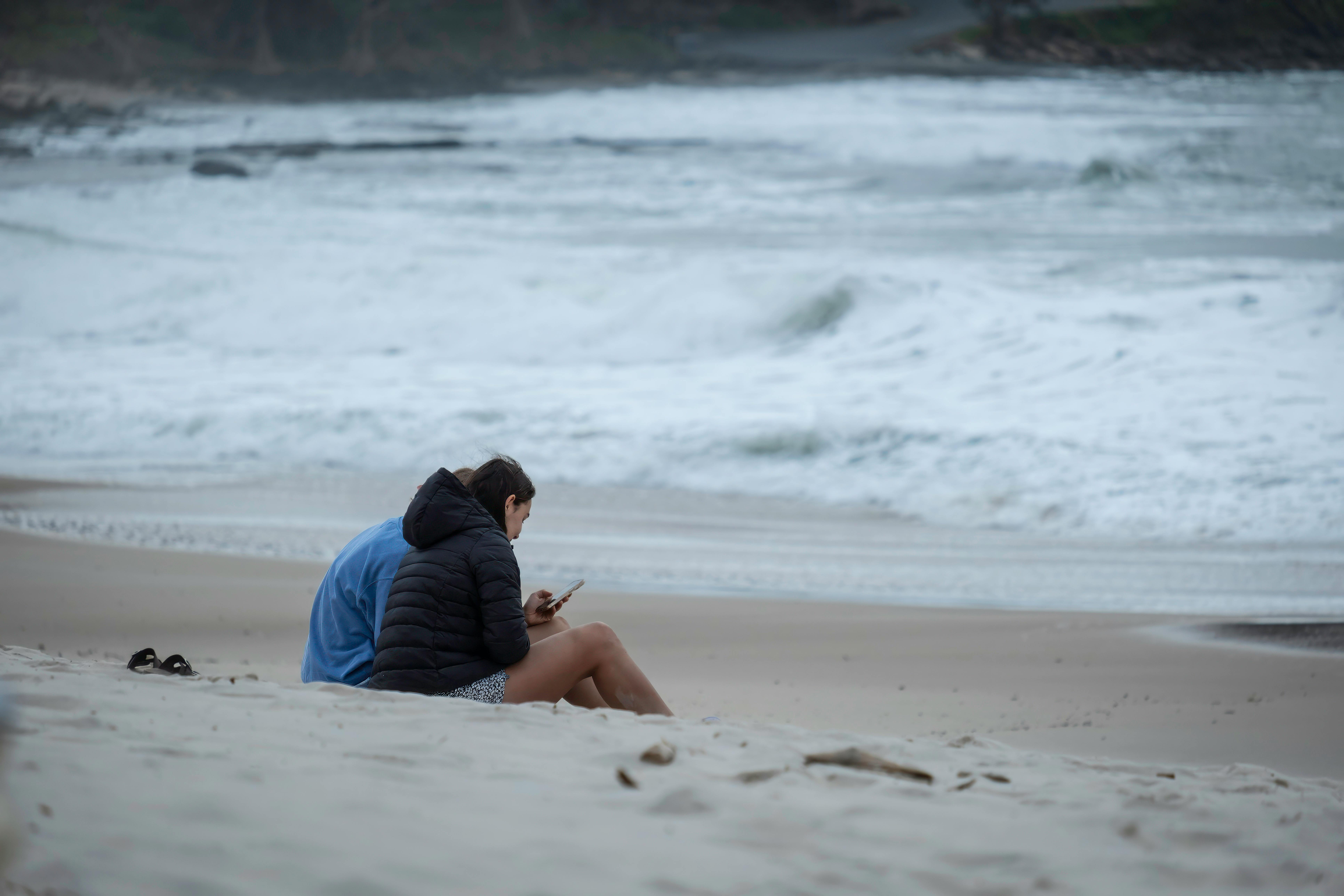 Two people sitting on a beach at dawn, enjoying the ocean view.